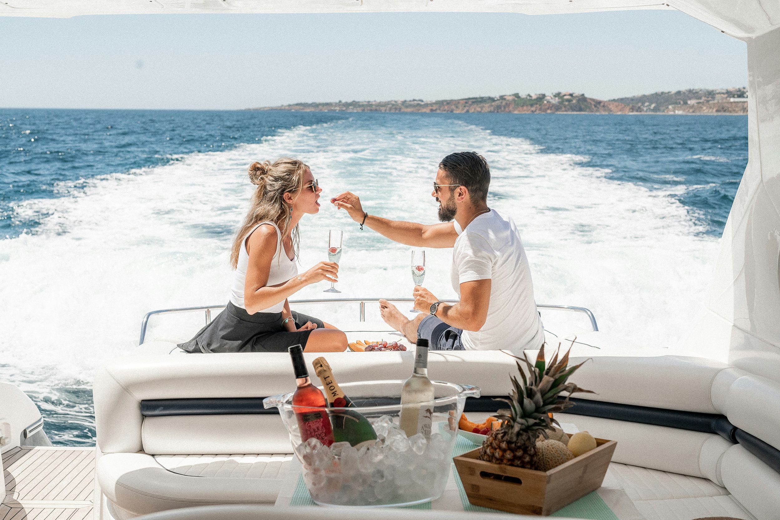 a man and a woman are drinking wine on a boat in the ocean .