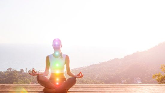 a woman is sitting in a lotus position on a wooden deck .