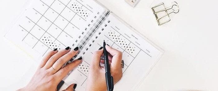 a person is writing in a calendar with a pen .