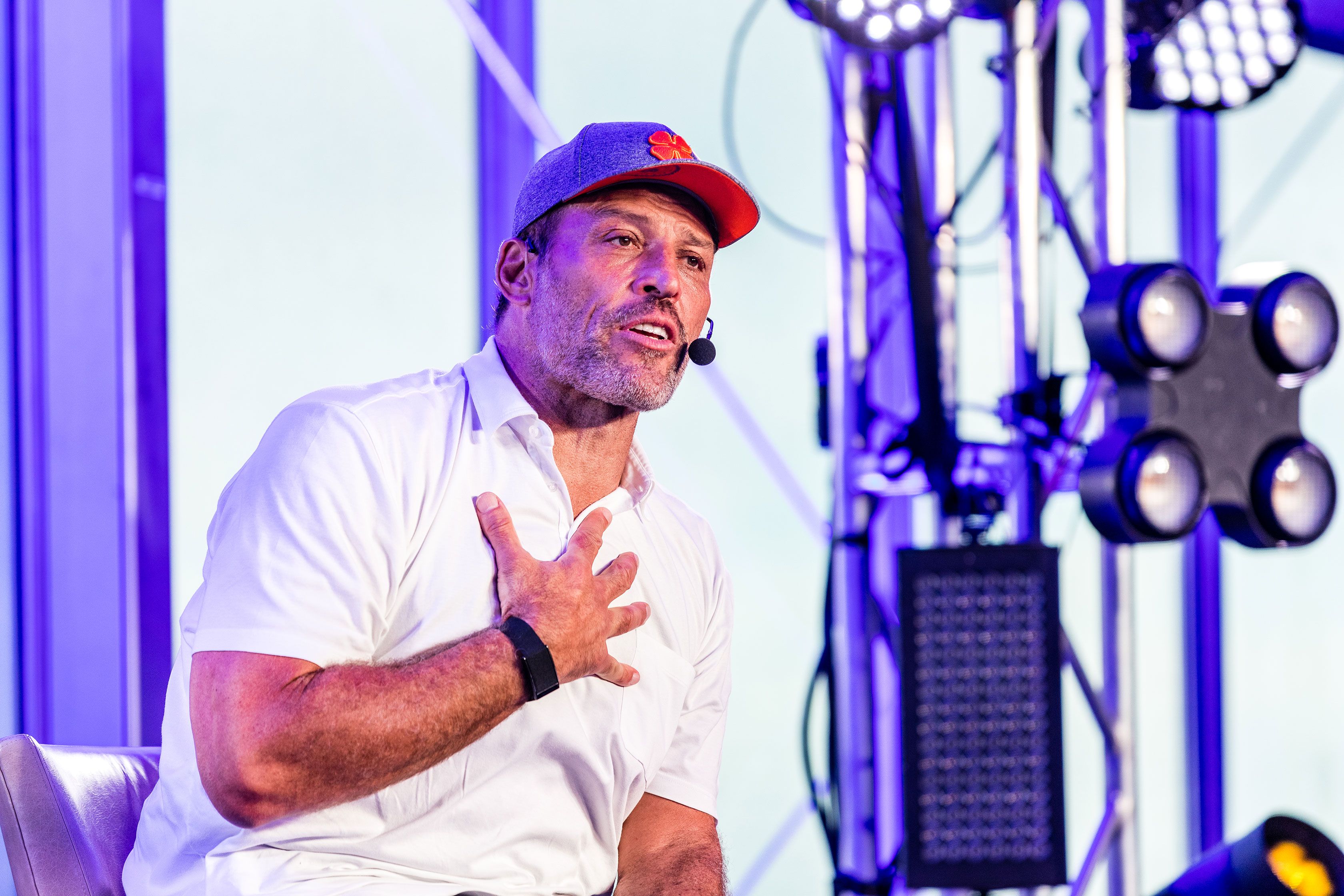 a man wearing a hat and a microphone is sitting in front of a stage .