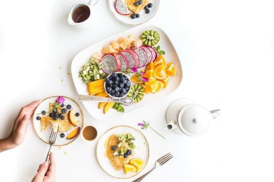 a person is sitting at a table eating a plate of fruit .