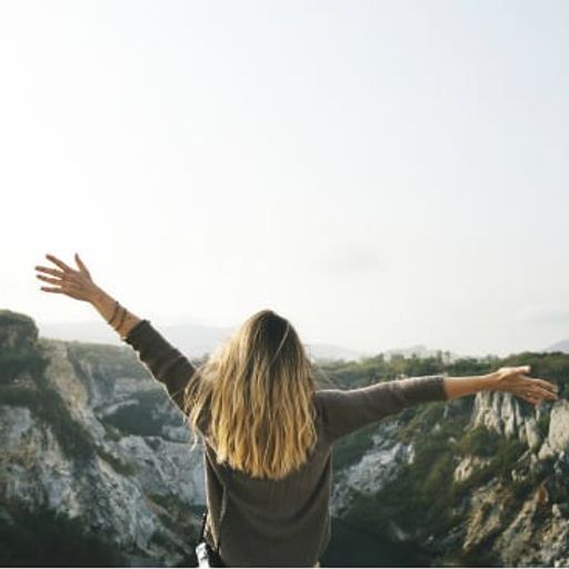 a woman is standing on top of a mountain with her arms outstretched .