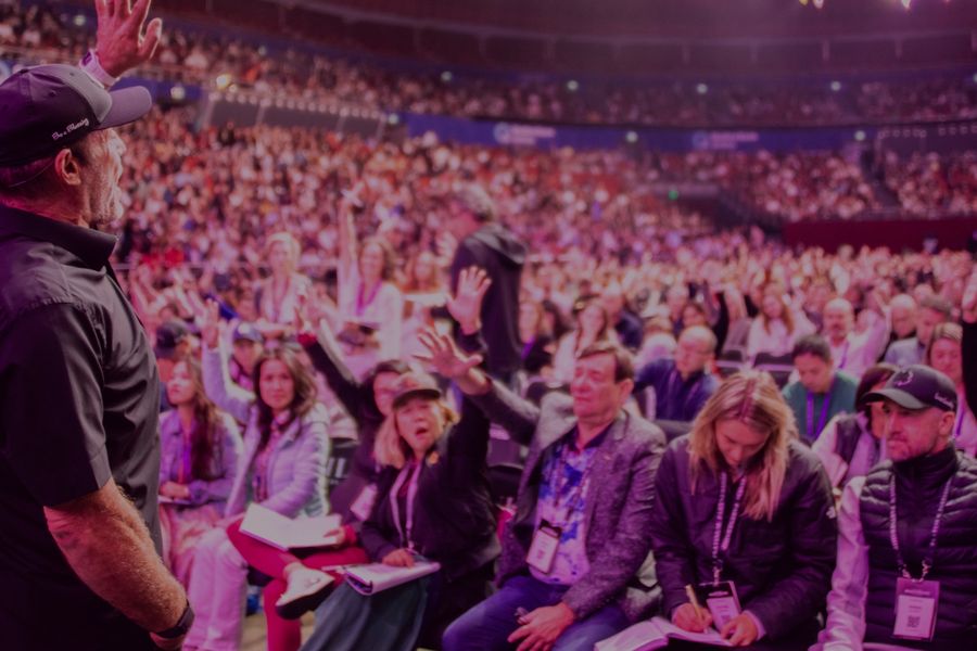 a man is standing in front of a crowd of people raising their hands in the air .