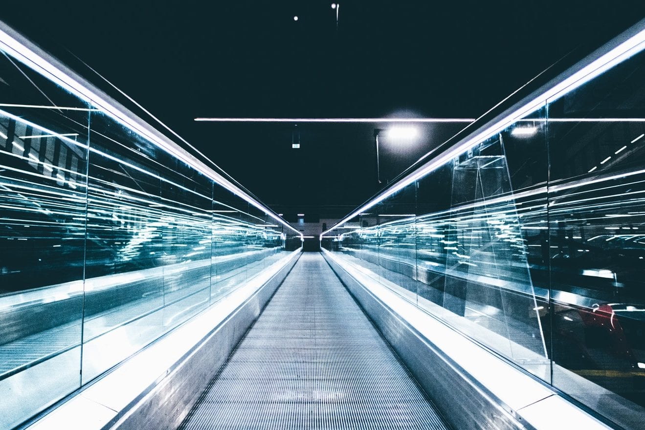 a long escalator in a dark tunnel with a lot of lights on it .