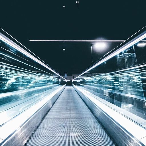 a long escalator in a dark tunnel with a lot of lights on it .