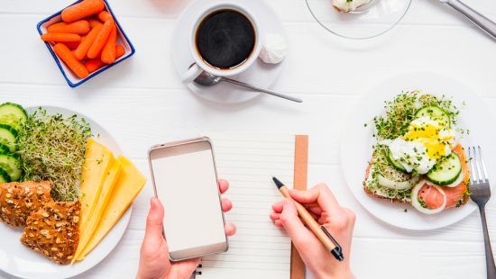 a person is holding a cell phone and writing in a notebook .