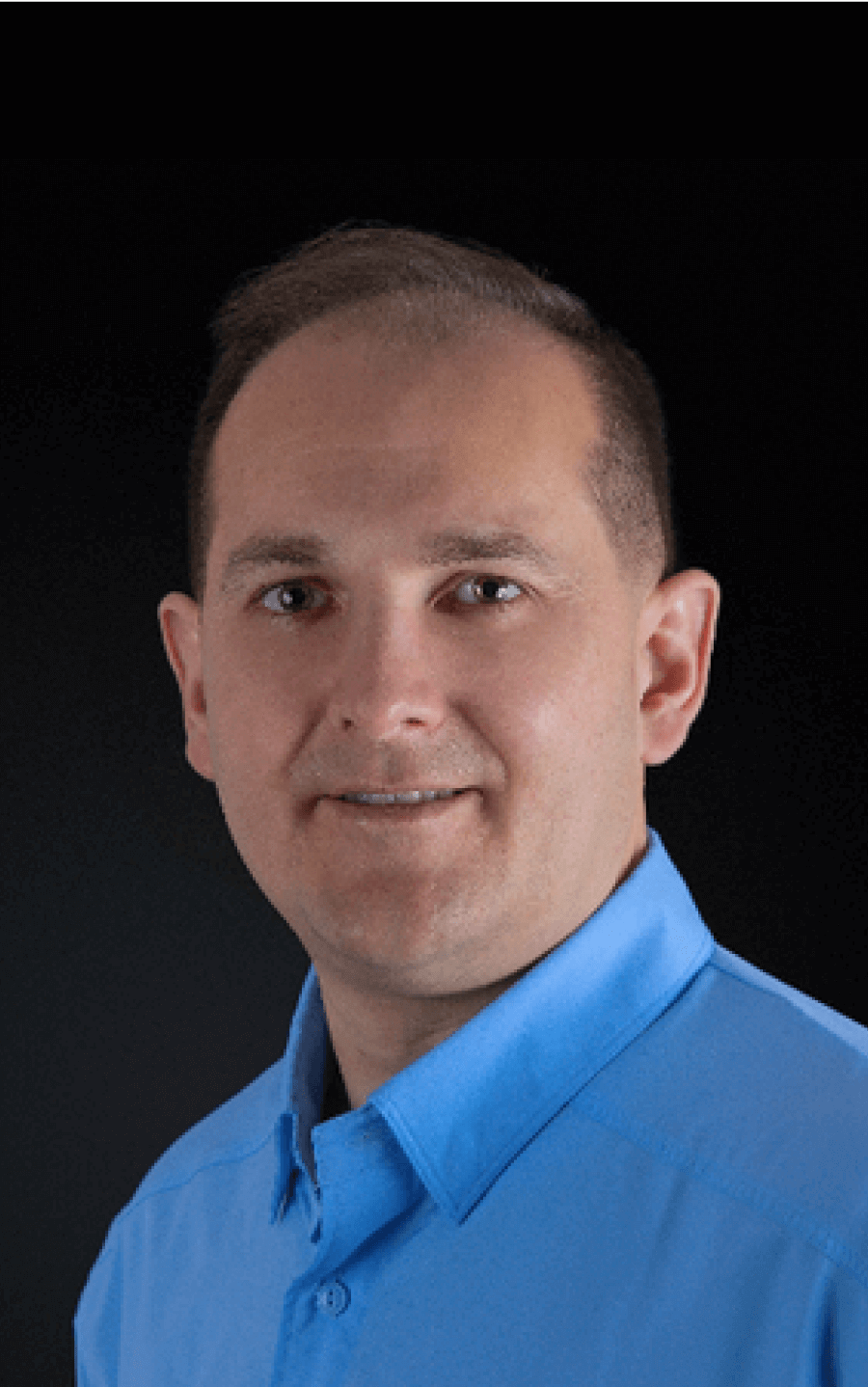 a man in a blue shirt is smiling for the camera