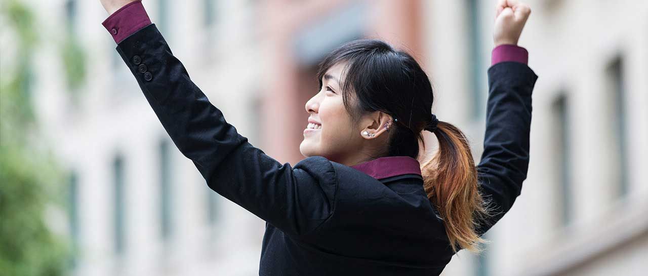 a woman in a suit is raising her arms in the air .
