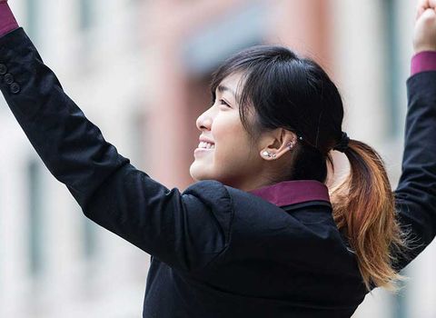 a woman in a suit is raising her arms in the air .