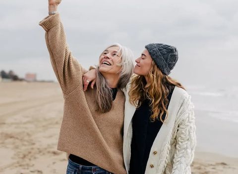 two women are standing next to each other on the beach .