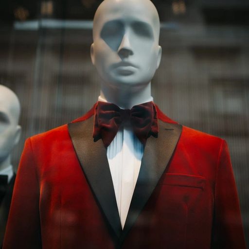 a mannequin is wearing a red tuxedo and bow tie .