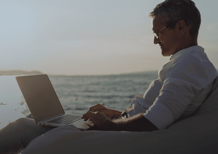 a man sits on a bean bag chair using a laptop