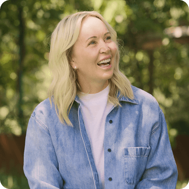 a woman wearing a blue denim shirt is smiling