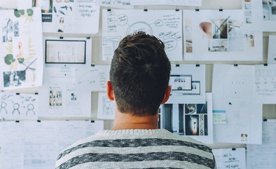 a man is looking at a wall full of papers .