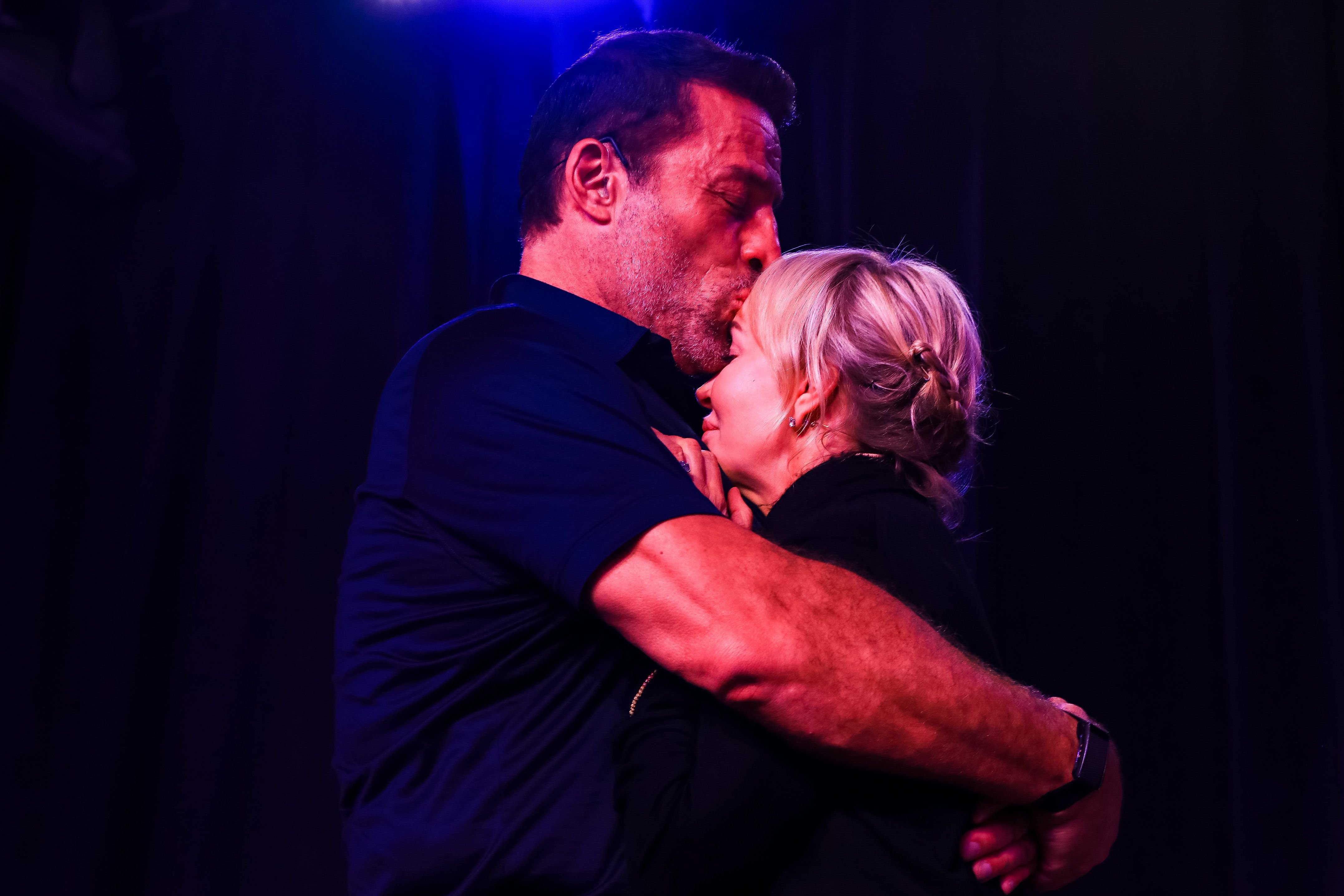 a man is kissing a woman on the forehead in a dark room .