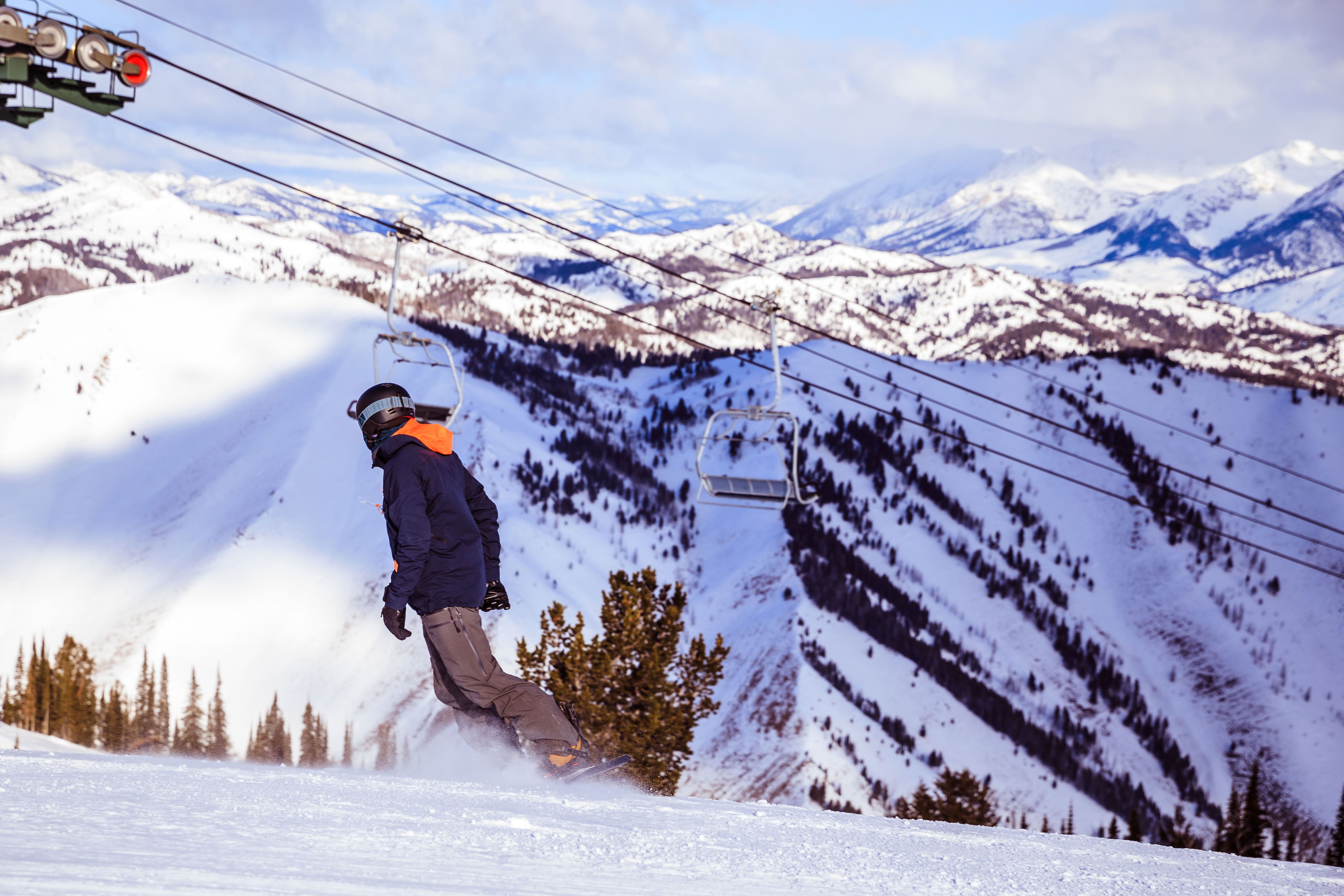 a man is snowboarding down a snow covered mountain .
