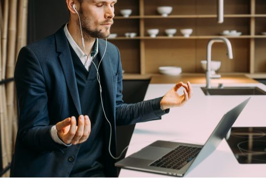 a man is meditating in front of a laptop computer while wearing headphones .