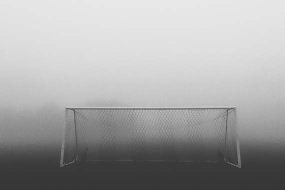 a black and white photo of a soccer goal in the fog .