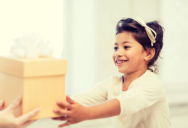 a little girl is holding a gift box in her hands .