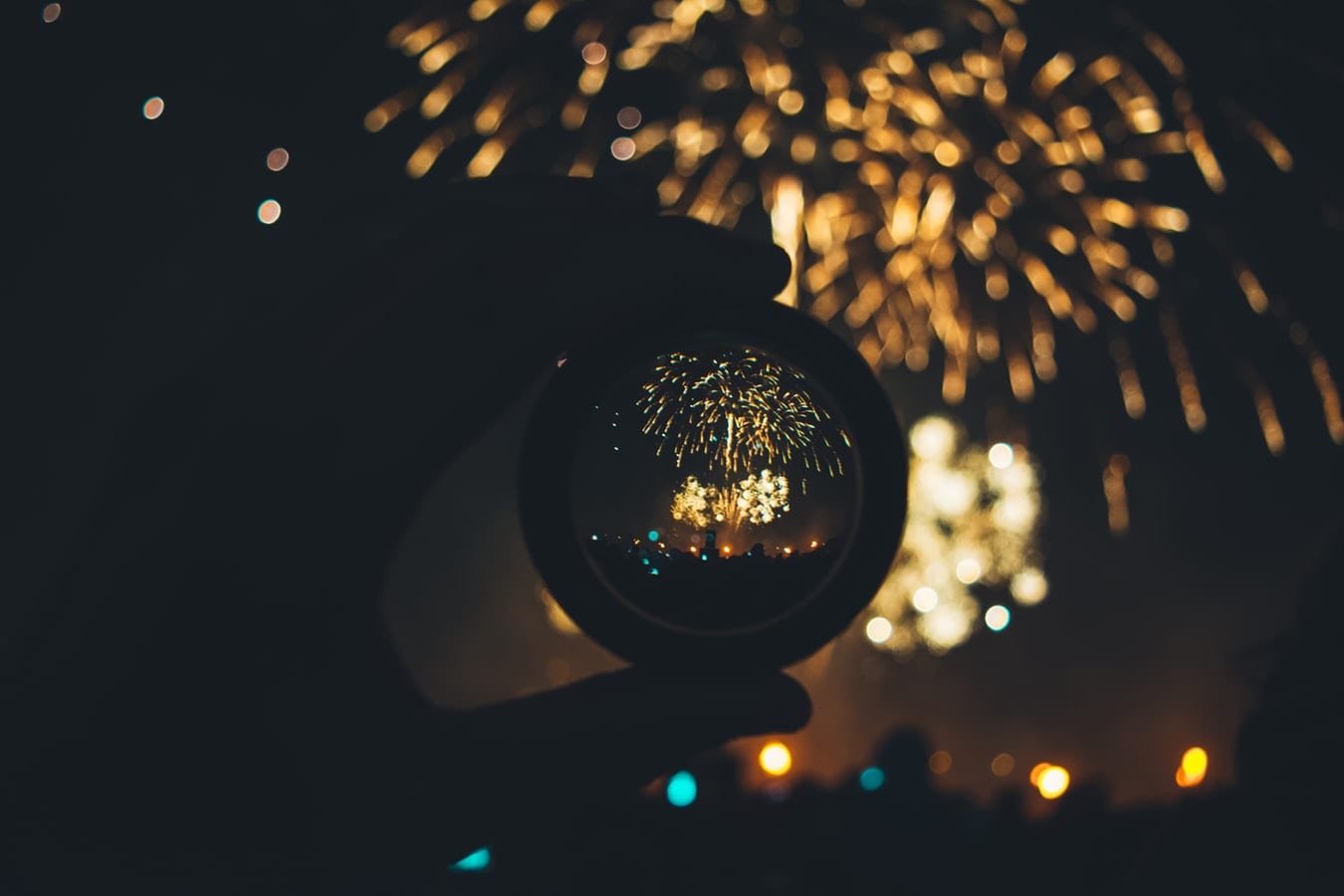 a person is holding a glass ball in front of a fireworks display .