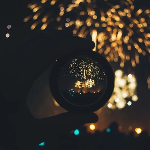 a person is holding a glass ball in front of a fireworks display .