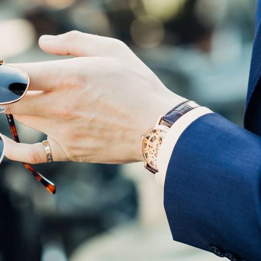 a man in a suit is holding a pair of sunglasses in his hand .