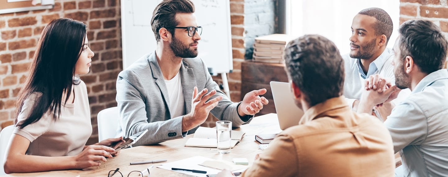 a group of people are sitting around a table having a meeting .