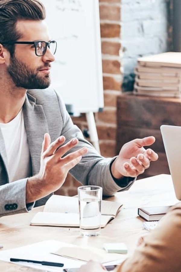 a group of people are sitting around a table having a meeting .