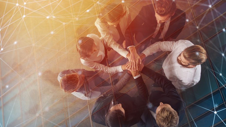 a group of business people are putting their hands together in a circle .