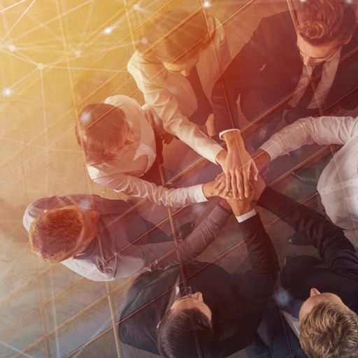 a group of business people are putting their hands together in a circle .