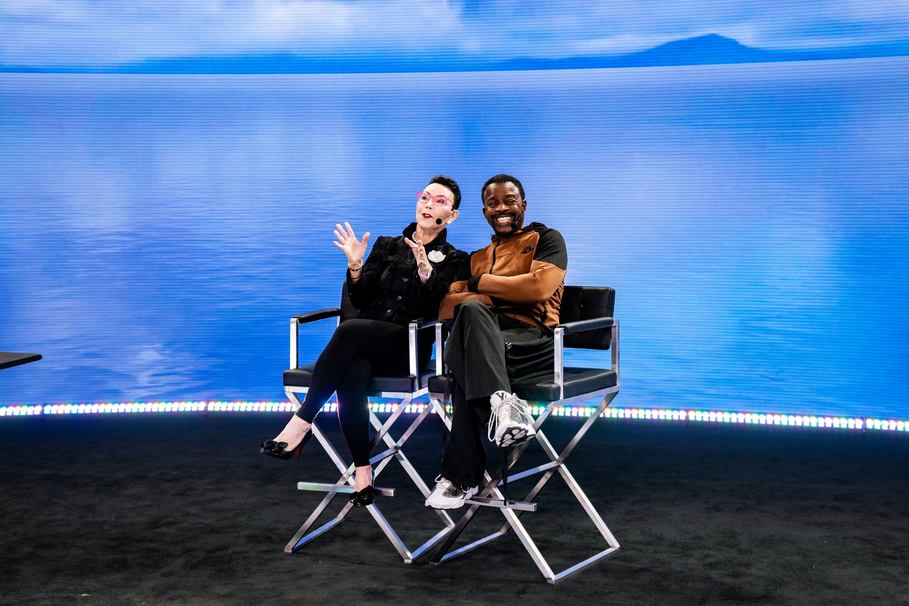 a man and a woman are sitting in director 's chairs in front of a body of water .
