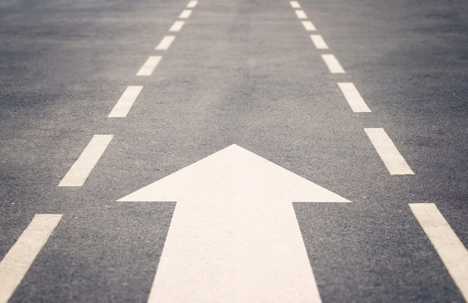 a white arrow is painted on the side of a road .