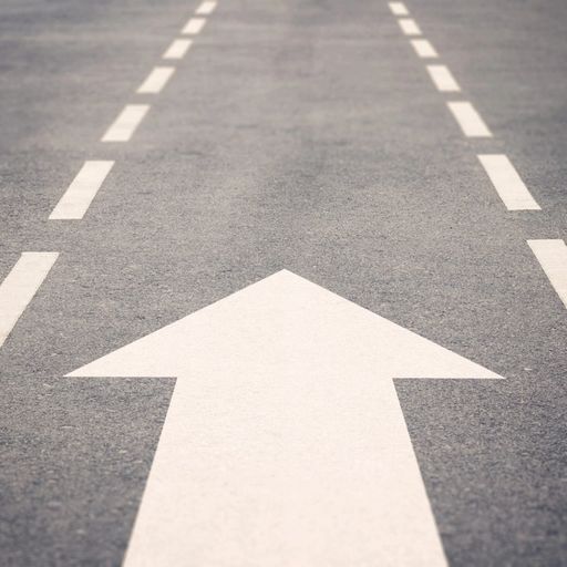 a white arrow is painted on the side of a road .