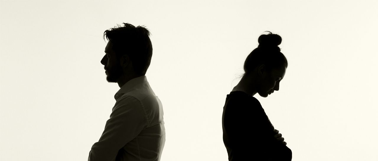 a man and a woman are standing back to back with their arms crossed .