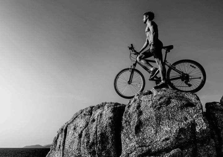 a man standing on a rock with a bike on top of it