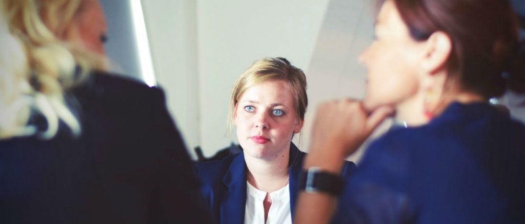 a group of women are sitting at a table having a conversation .