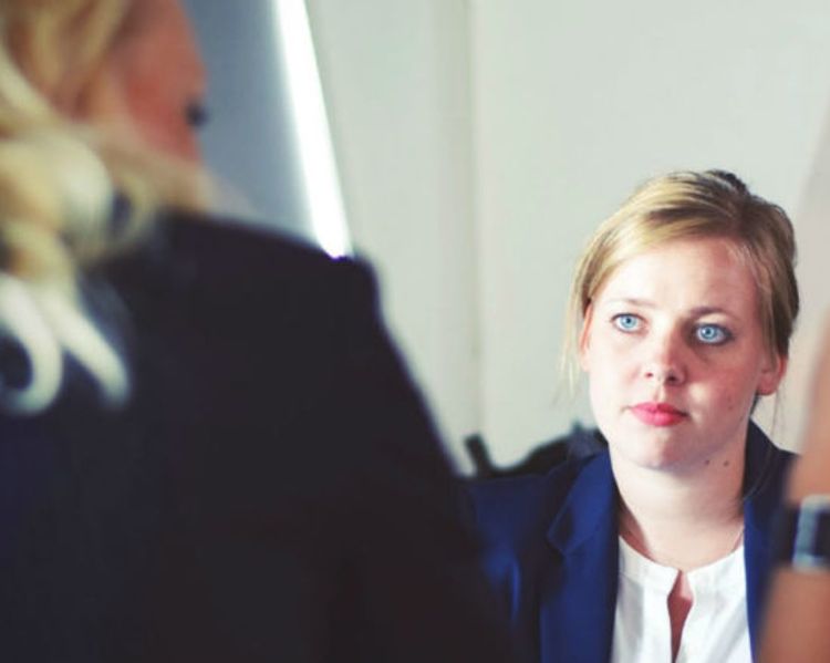 a group of women are sitting at a table having a conversation .