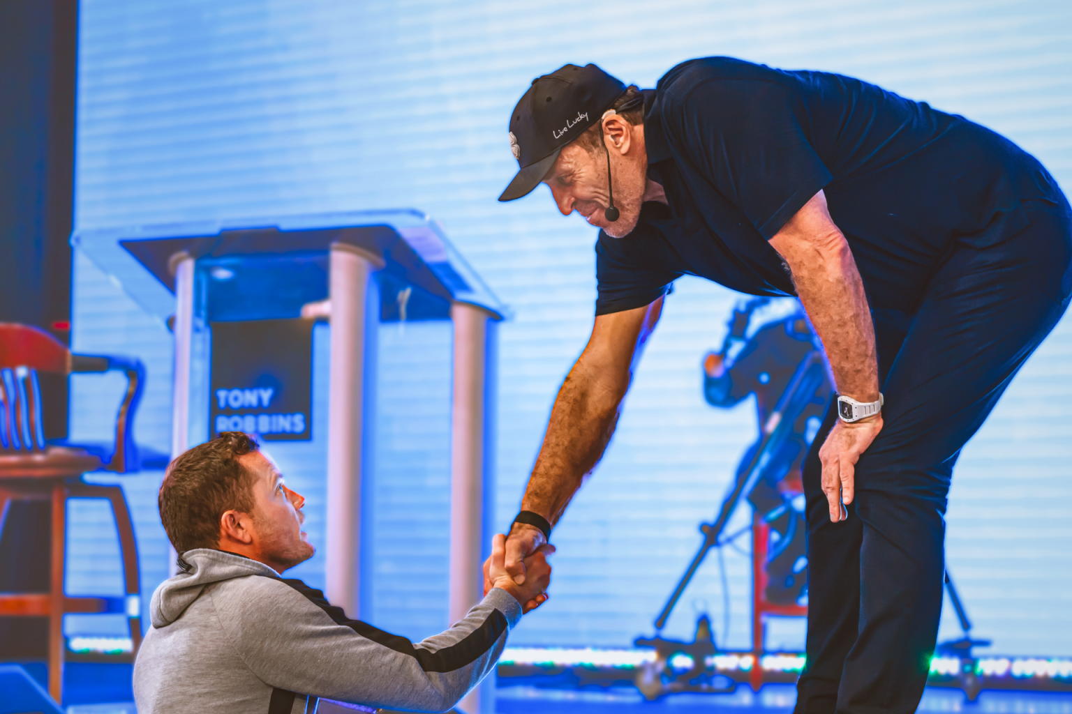 two men shake hands in front of a sign that says tony robbins