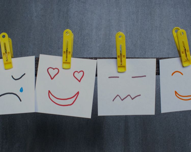 a row of sticky notes with different facial expressions hanging on a clothes line .