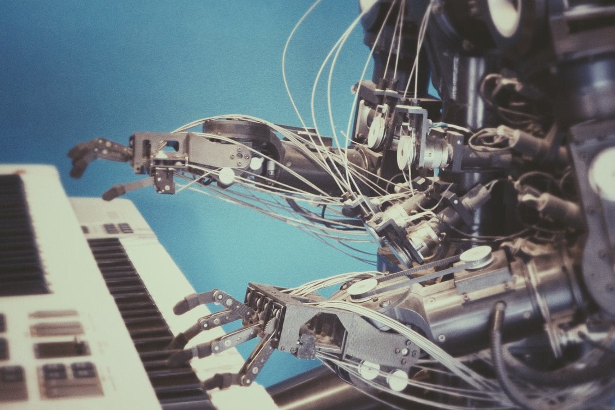 a robot is playing a piano next to a keyboard .