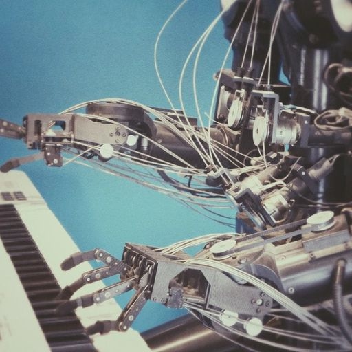 a robot is playing a piano next to a keyboard .
