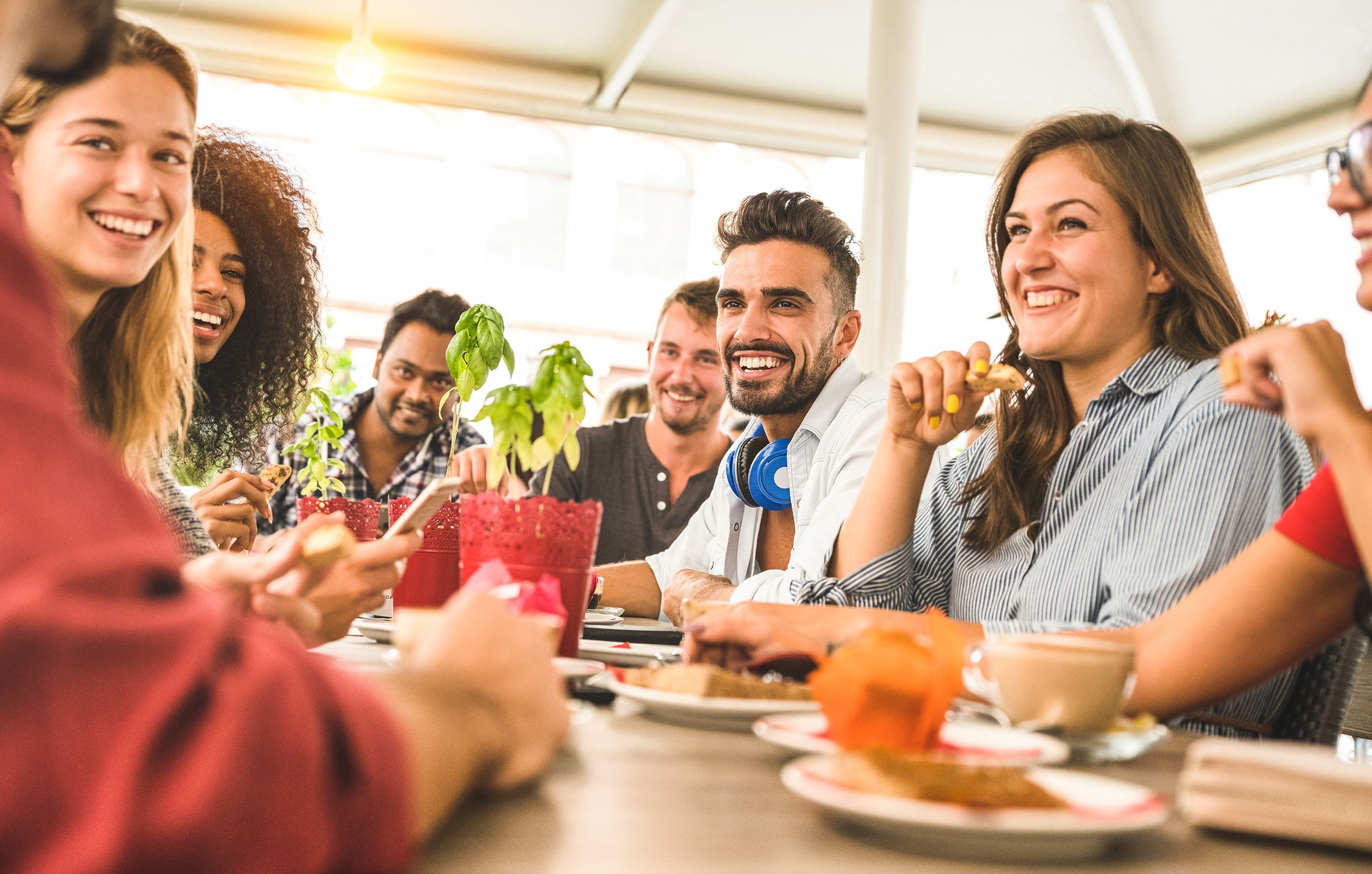 a group of people are sitting at a table eating food and drinking coffee .