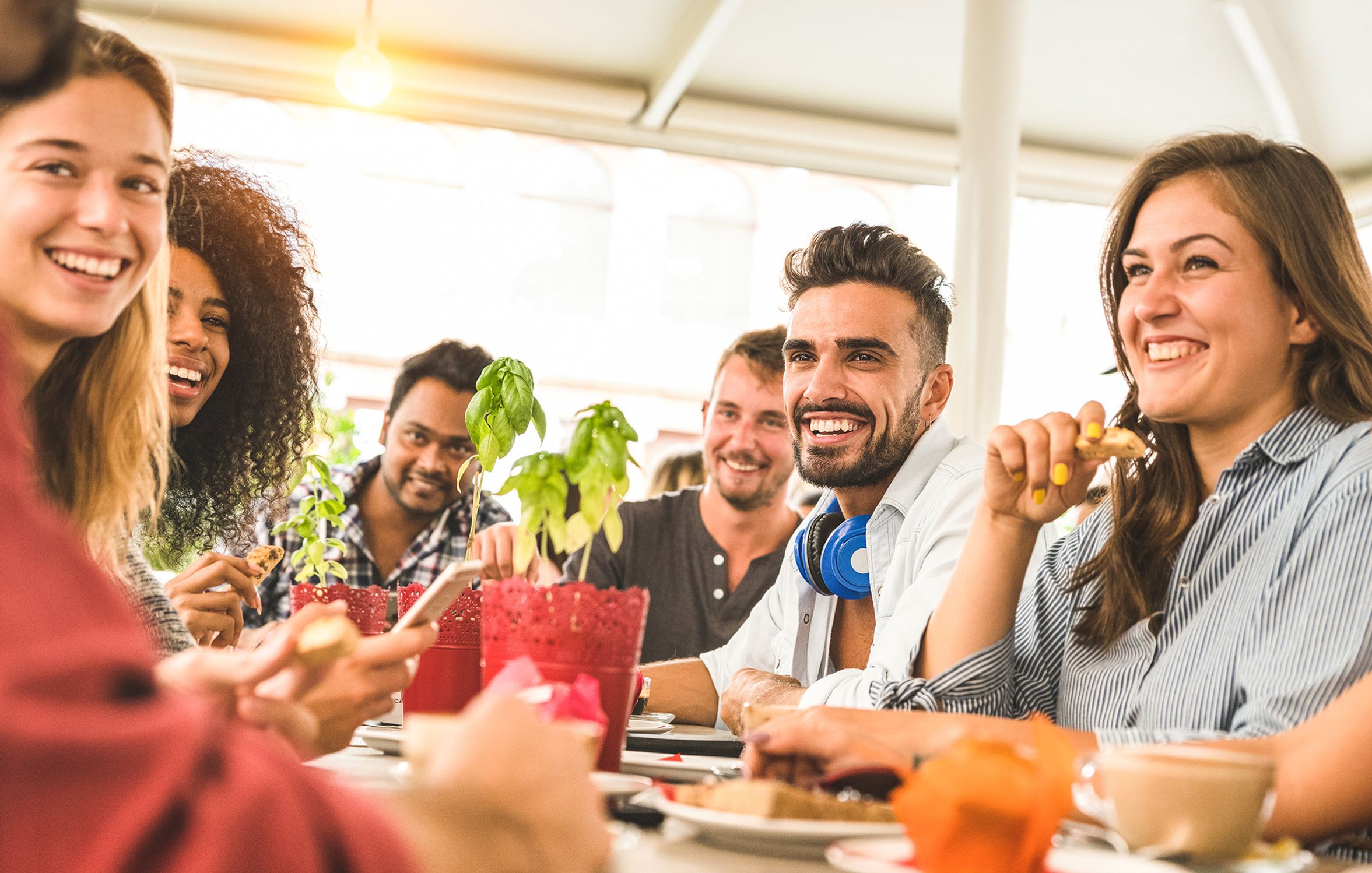 a group of people are sitting at a table eating food and drinking coffee .