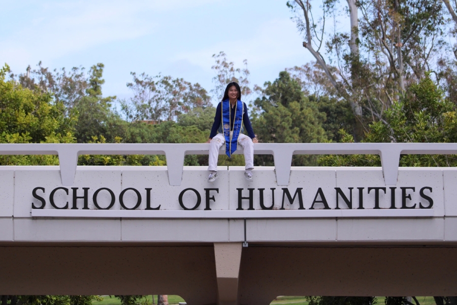 Girl sitting on school sign.
