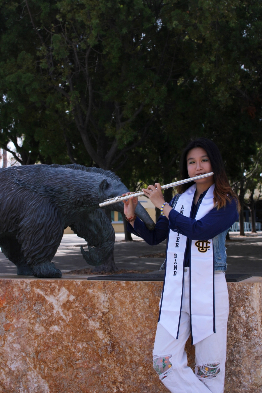 Girl playing the flute in front of anteater statue.