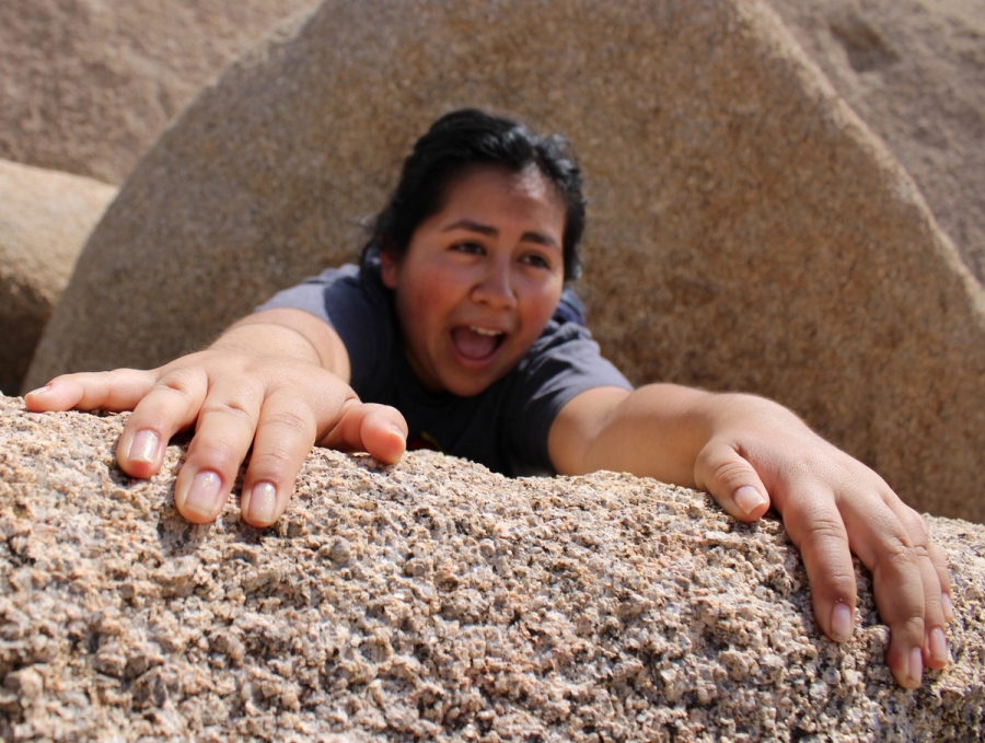 Mexican girl looking like she's hanging off a rock.