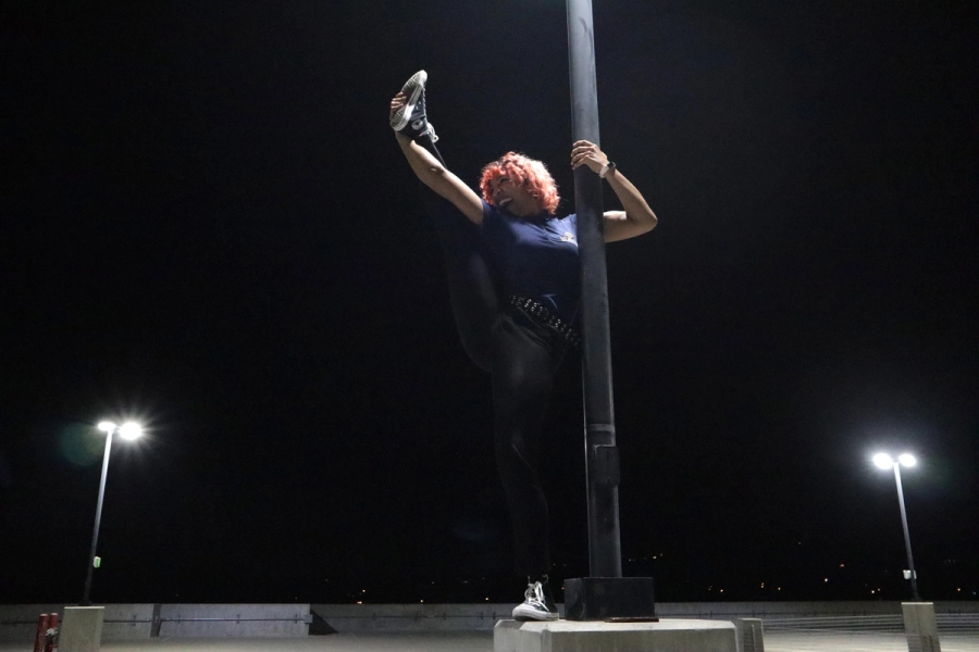 Girl holding up leg on lamppost.