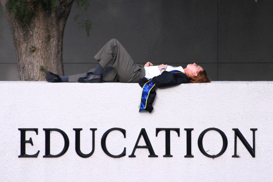Girl laying on school sign.