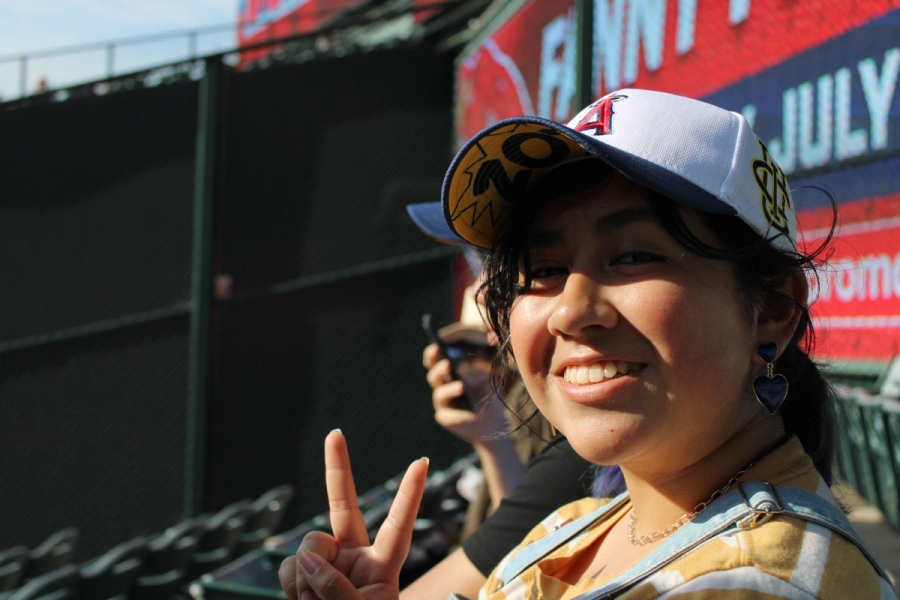 Girl holding peace sign with hat.