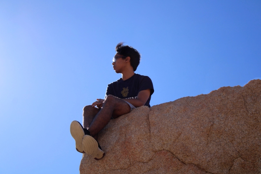 Filipino boy sitting at the edge of rock.